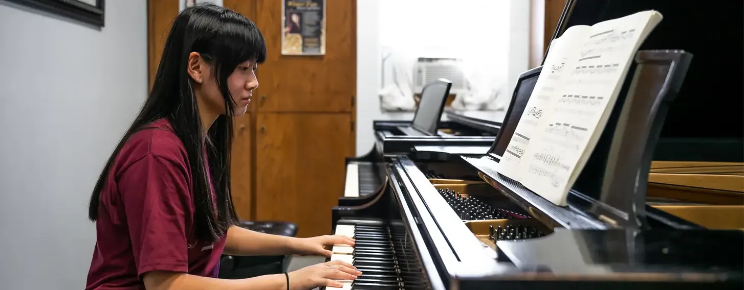 Woman sitting at the piano with her hands on the keys.